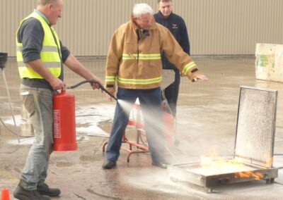 Fire safety trainer supervising a participant tackling a tray fire