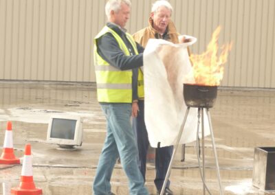 Course participant placing a fire blanket over a pan fire